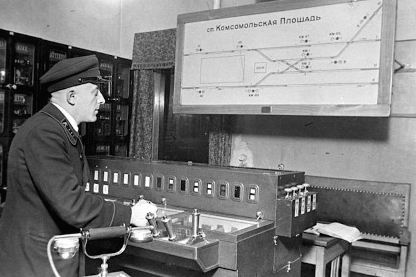 Дежурный блокпоста централизации станции "Комсомольская" за работой, 1935 год. Примечательно, что табло со схемой путевого развития участка было установлено годом ранее (до начала пассажирского движения), поэтому здесь ещё запечатлено проектное название станции — "Комсомольская площадь"