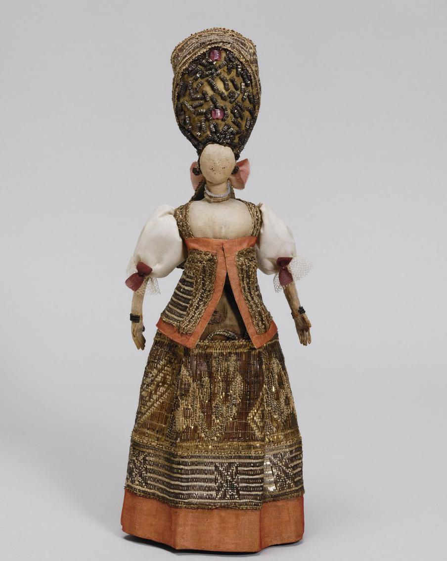 Кукла. Россия, конец XVIII – начало XIX вв. Полотно, холст, галун, тесьма, нити золотные, стёкла, бумага, атлас; ткачество, набойка. Находилась в экспозиции Палат бояр Романовых. Музеи Московского Кремля.