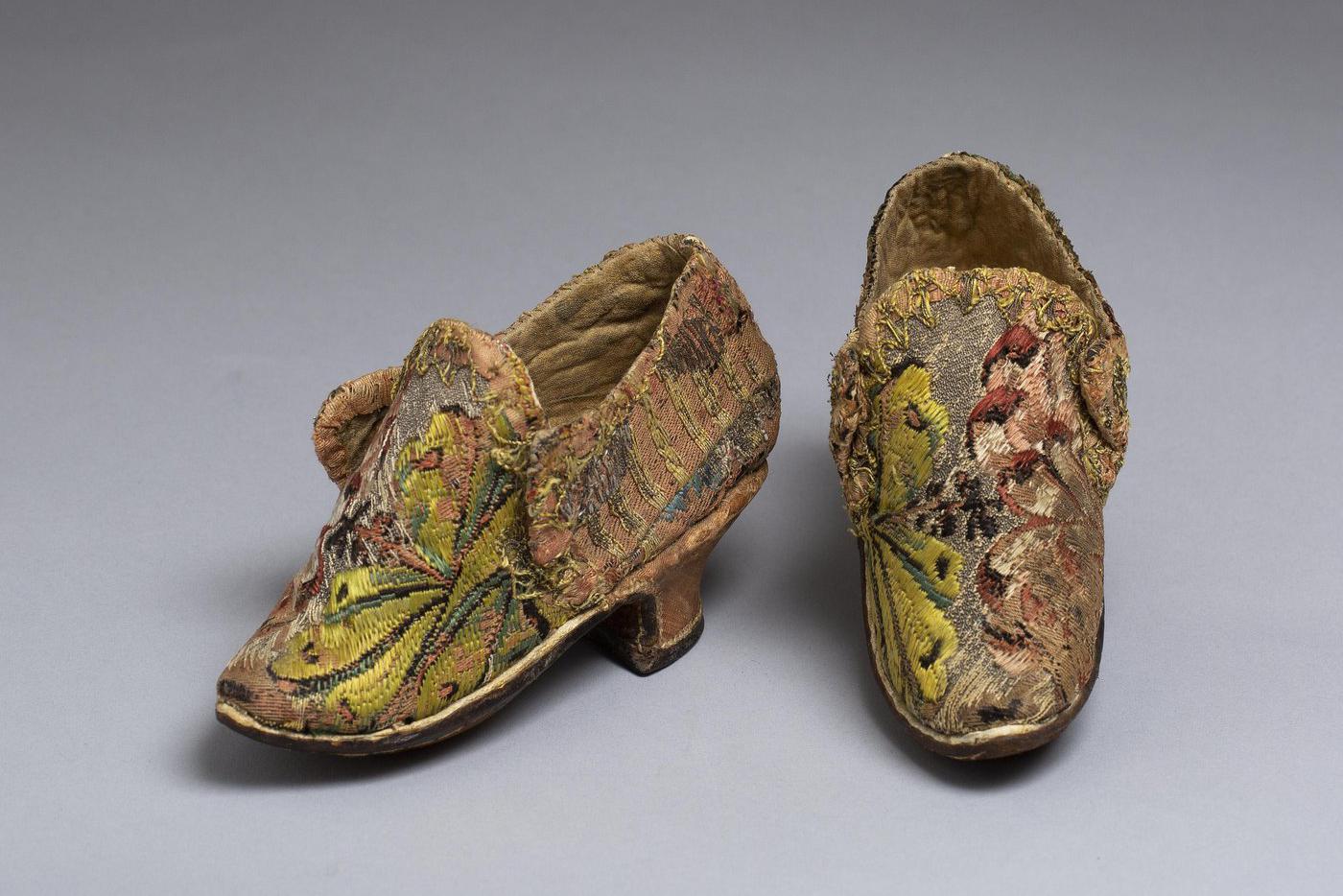 Башмачки, пара. Из собрания Оружейной палаты. Экспонировались в Палатах бояр Романовых. Россия, первая четверть XVIII в. Кожа, парча, тесьма, шёлк; ткачество. Музеи Московского Кремля.