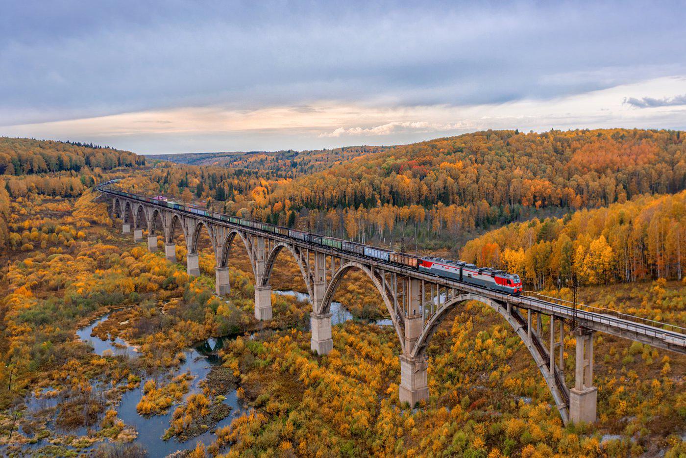 Уральская осень. Саранинский лог – один из семи уникальных виадуков, построенных более ста лет назад в западной части Свердловской области, в окрестностях города Красноуфимска. В этих местах Казанский ход Транссиба пересекает Сылвинский кряж, где между холмами через долины рек в 1914–1919 годах и было построено семь уникальных виадуков. Часть из них уже нерабочие и являются лишь памятниками инженерного искусства. Но 100-летний виадук Саранинский лог с его десятью пролётами до сих пор в рабочем состоянии.