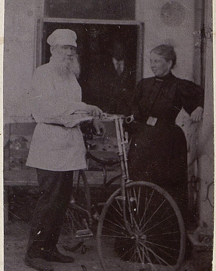 Лев Толстой стоит около дома с велосипедом, справа Софья.1896 год.