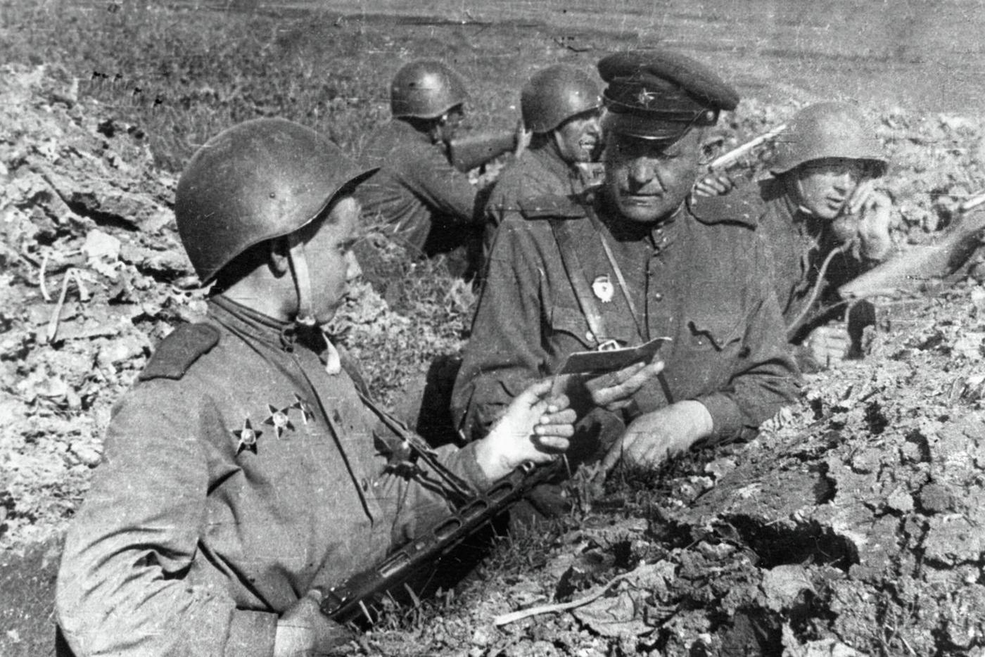 Батальонный комиссар вручает бойцу комсомольский билет на передовых позициях. 3-й Украинский фронт.
