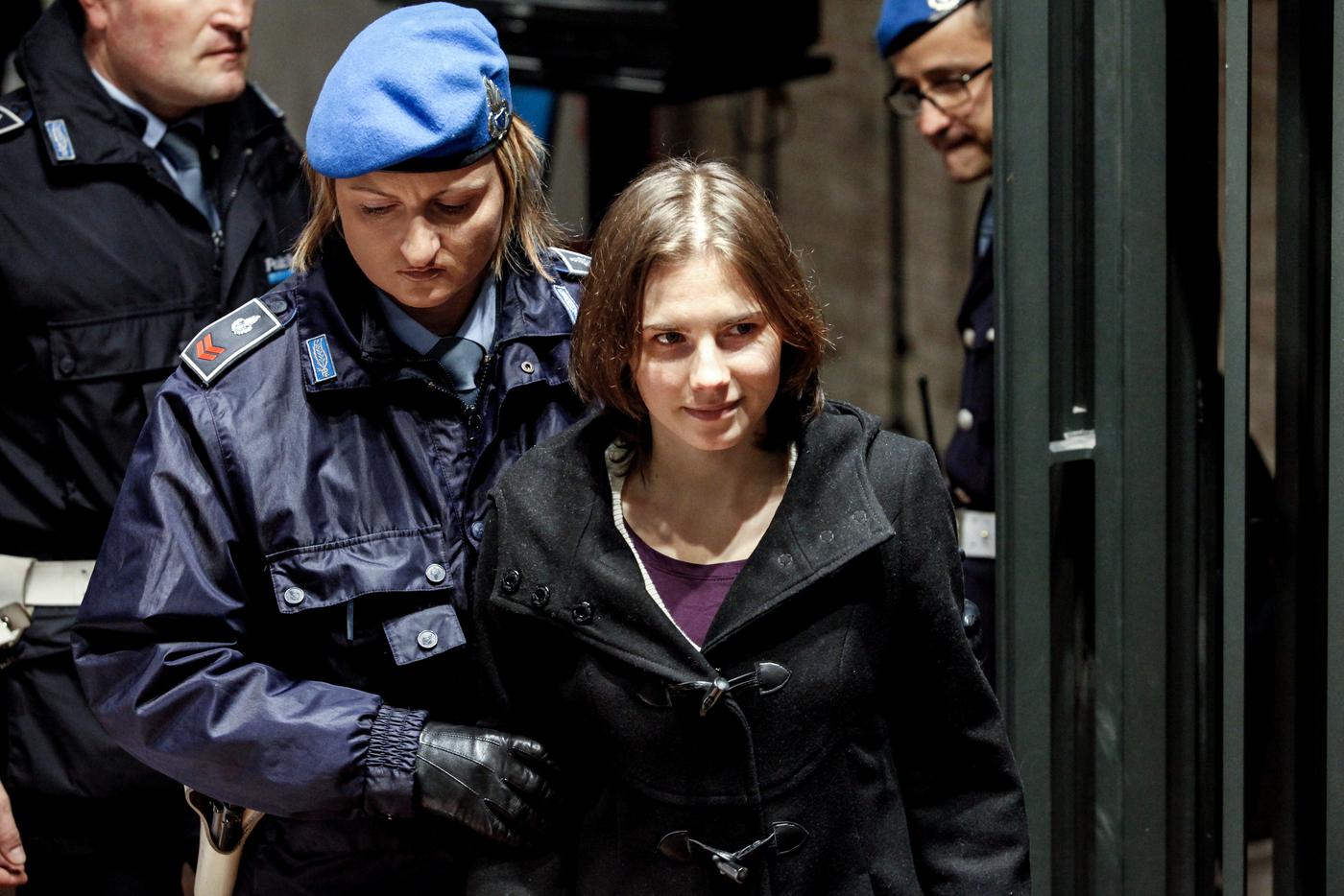 Аманда Нокс в сопровождении женщины-полицейского.