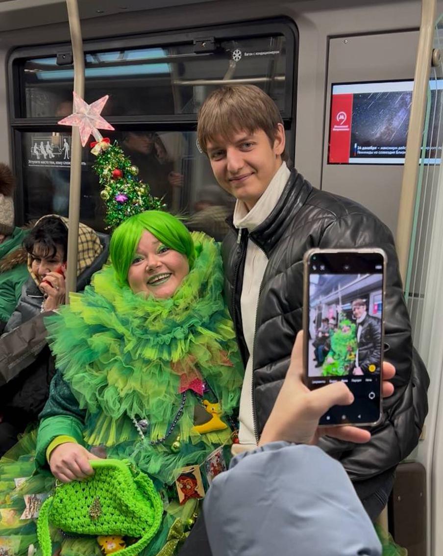 За рукой с телефоном не видно, но парень озарён улыбкой, потому что сидит у ёлки на коленках.