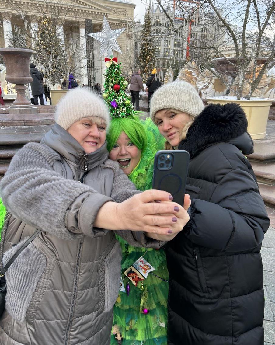 Приглядитесь: москвичи на фоне одеты в сплошь серо-чёрной гамме. Как тут не повеселеть при виде настолько яркой и объёмной женщины-ели? 