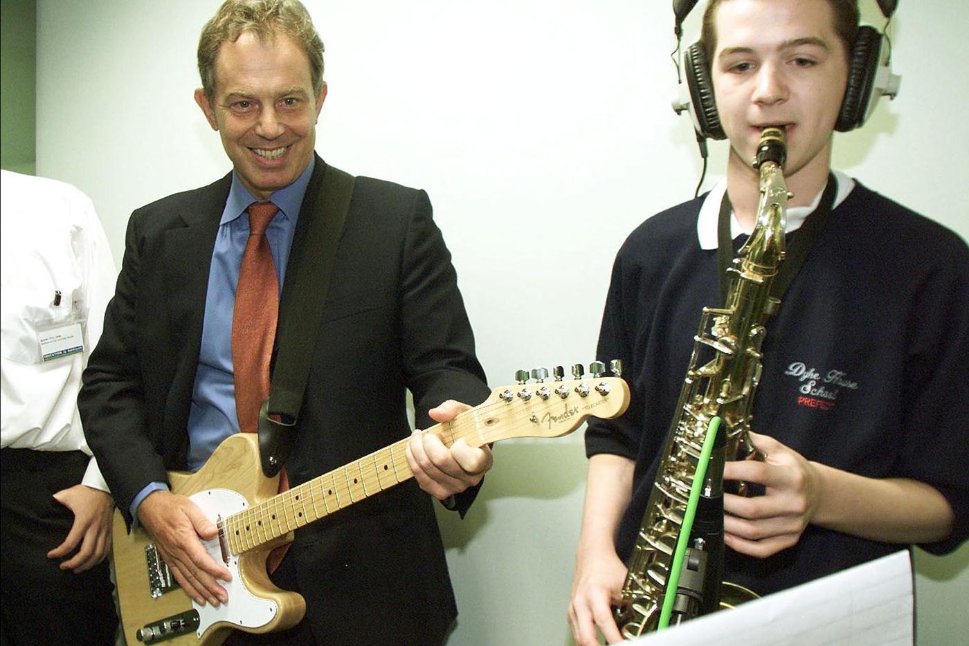 ALL Тони Блэр (слева) играет на гитаре вместе с учеником-саксофонистом Эндрю Крэггом во время визита в Городской учебный центр при школе Дайк-Хаус в Хартлпуле.