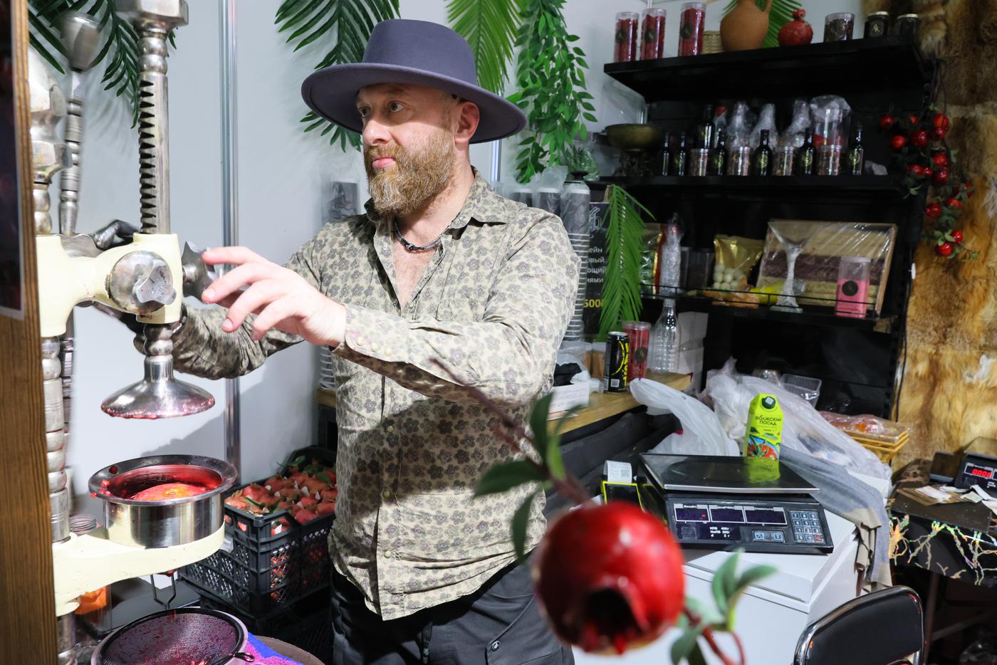 Импозантный мужчина в шляпе и бусах давил гранатовый сок своими руками для всех желающих.