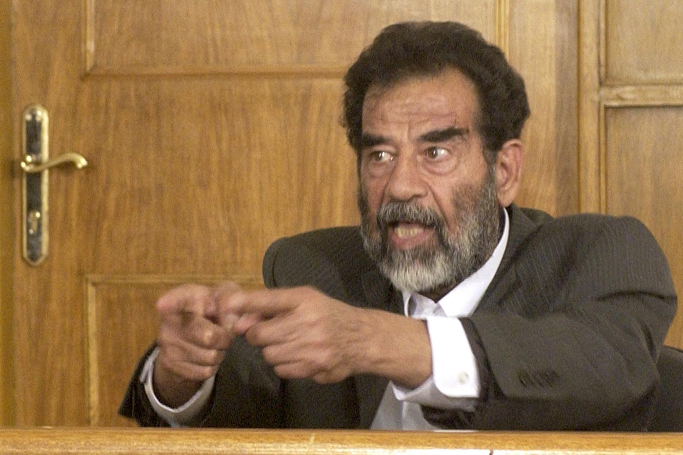 Саддам Хусейн беседует с судьей в неизвестном месте в Багдаде, где ему сообщают о ряде обвинений, в том числе в геноциде