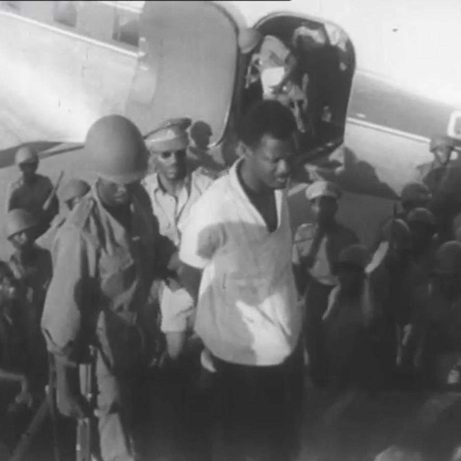 Архивные кадры пересадки пленнёного Патриса Лумумбы в самолёт DC-4 в сопровождении военных.