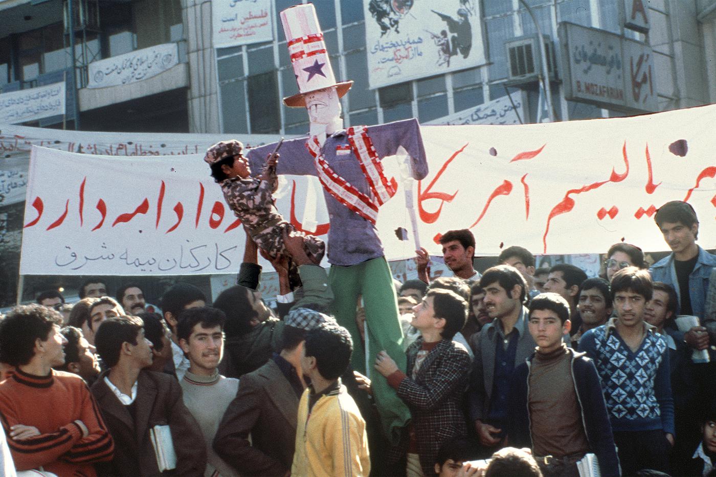 IRAN-U.S. HOSTAGES Мальчик в камуфляжной форме во время демонстрации целится игрушечным пистолетом в изображение президента США Картера незадолго до взятия посольства США в Тегеране.